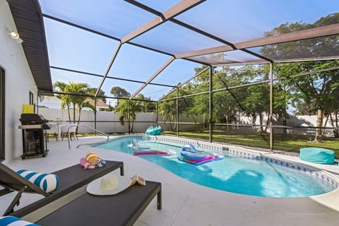 Your outdoor oasis awaits! A fully screened pool cage with outdoor grill, table and loungers for guests enjoyment