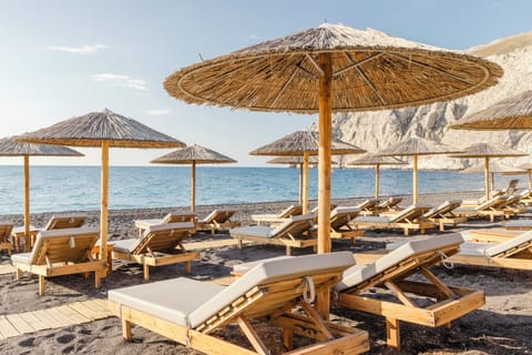 On the beach, black sand, sun loungers, beach umbrellas