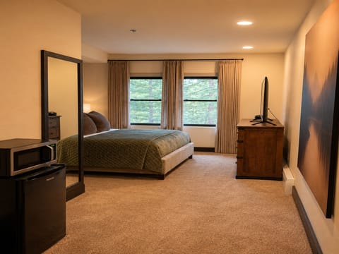 Settle into your serene retreat with plush bedding and peaceful tree-lined views. Natural light fills the room through elegant curtains, while thoughtful touches like the mini-fridge and warm wood accents make you feel right at home.