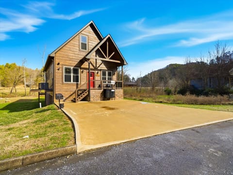 Charming wooden cabin with red door nestled among rolling hills and natural landscape, featuring ample parking space.