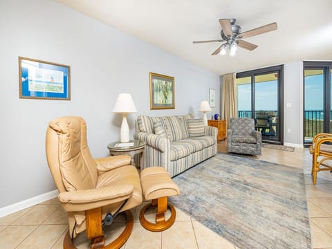 Cozy living area features a striped sofa with queen sleeper, accent chairs, and a view of the balcony