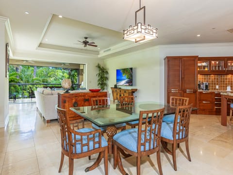 Gather with loved ones at your dining table, where a ceiling fan keeps the breeze flowing and tropical greenery awaits just beyond the open terrace doors.