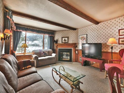 Living room features a flat screen TV, gas fireplace, flowered wallpaper