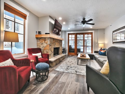 Bright open living room with red accent arm chairs and sliding patio doors to private deck