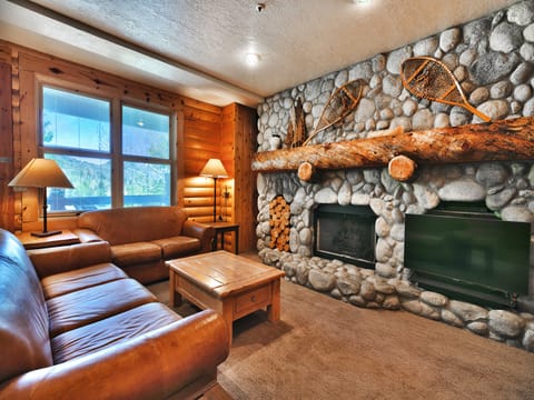 Feature river rock fireplace wall with flat screen TV and large log fireplace mantle