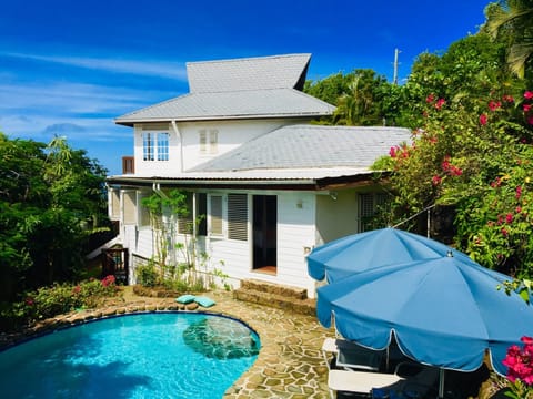 Side profile of house, surrounded by lush tropical plants.