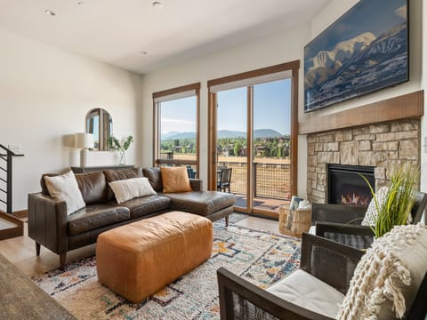 Gather in this intimate corner with a stone fireplace, flat screen TV, and mountain views - Sink into the plush sectional or enjoy a chat in the comfy accent chairs nearby - Sliding doors lead to the balcony with wide open scenic landscapes