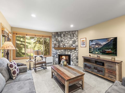 The warm and inviting living room with a river rock hearth and gas burning fireplace.