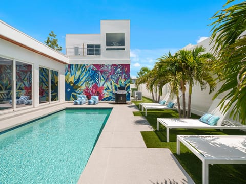 Modern tropical oasis with vibrant mural, sparkling pool, and lounge chairs framed by swaying palms—perfect for sunny relaxation in style.
