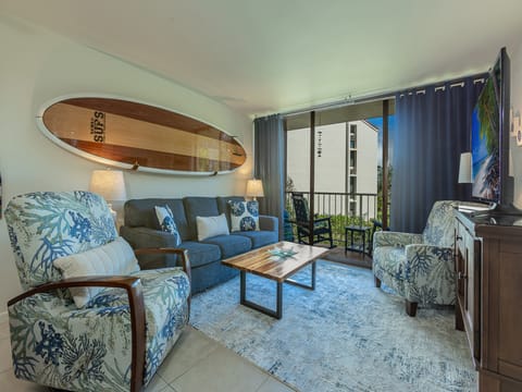 Relax in your tropical-inspired living room where coastal charm meets comfort—complete with surfboard art and ocean breezes from your private balcony.
