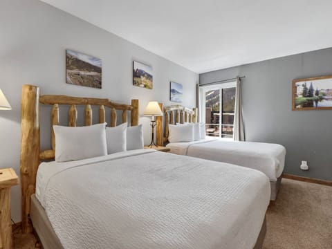 Unwind in your comfortable twin bedroom with rustic log beds, crisp linens, and mountain artwork creating a cozy alpine retreat.