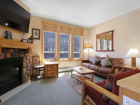 Cozy up by your stone fireplace in this warm living space with leather seating and mountain village views.