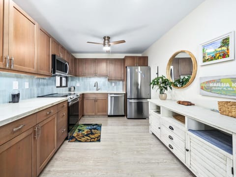Your fully equipped kitchen features warm wood cabinetry, stainless steel appliances, and a refreshing coastal vibe—perfect for preparing meals together during your island getaway.