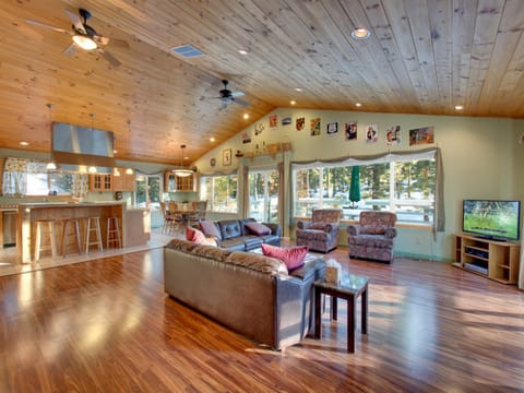 Cozy open-concept living area with vaulted wood ceilings, a fireplace, and plenty of natural light.