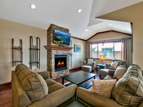 Cozy living room with a stone fireplace, plush seating, and vaulted ceilings