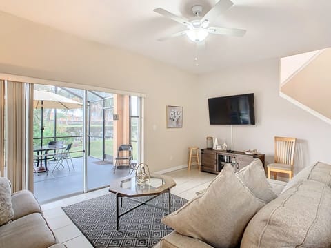 Cozy living room with a flat-screen TV and natural light, opening to a relaxing patio.