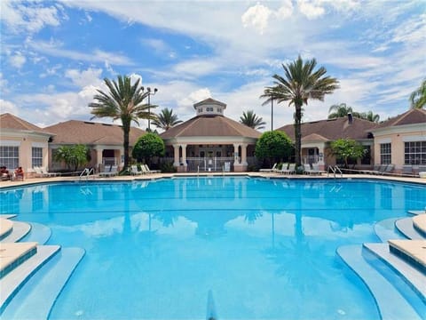 Expansive resort-style pool surrounded by palm trees and relaxation areas.