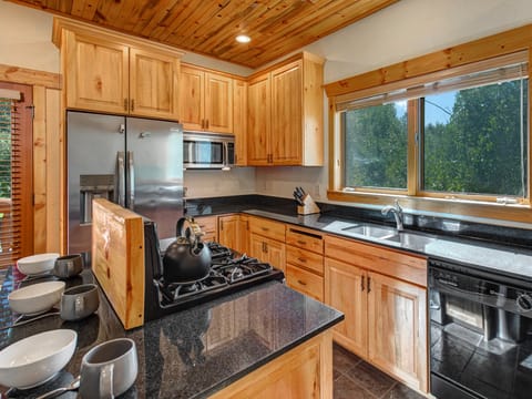 The well equipped kitchen has stainless appliances, black granite counters, and wood cabinets.