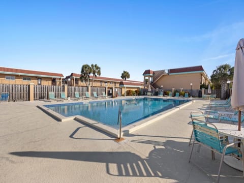 Sunny pool area with ample loungers and clear blue skies for a revitalizing swim.
