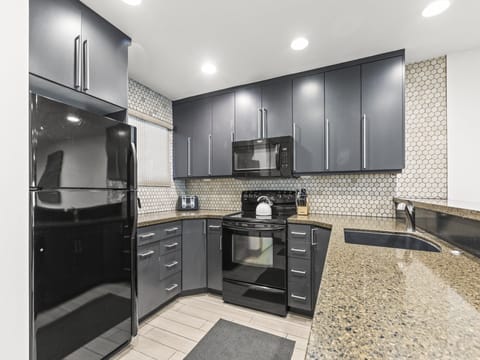 Snow Flower 126 offers a well equipped kitchen with grey cabinets, granite countertops, and tiled backsplash.