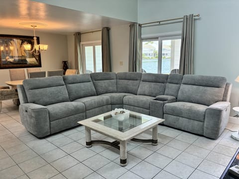 Sink into your spacious sectional sofa and unwind while enjoying stunning water views through floor-to-ceiling windows in this elegant living space.