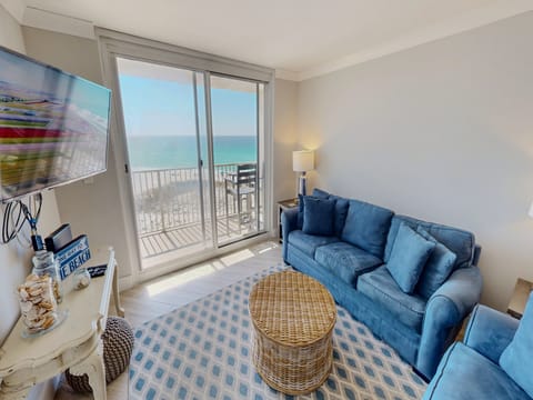 Relax on plush blue sofas while enjoying stunning ocean views through floor-to-ceiling windows in your bright, coastal living room.