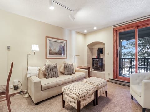 Sink into plush seating by your crackling fireplace, where snowy mountain views frame perfect winter evenings through expansive windows.