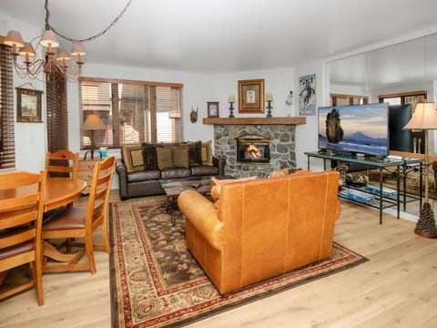 Cozy up in your spacious living room where a crackling stone fireplace, rich leather seating, and warm wood accents create the perfect mountain retreat for unwinding after a day of adventure.