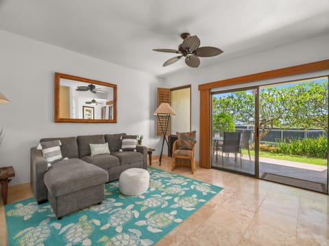 Unwind in your bright, airy living space with tropical ceiling fan, plush seating, and direct patio access to lush greenery and outdoor dining. Pure island comfort awaits.