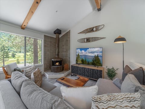 Unwind in your cozy living room with vaulted ceilings, exposed beams, and a crackling fireplace that sets the perfect mountain retreat ambiance. Sink into plush sofas and enjoy breathtaking forest views through expansive windows.