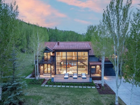 A stunning mountain retreat nestled among aspen groves and evergreens, featuring modern architecture with floor-to-ceiling windows and an expansive deck perfect for soaking in the natural beauty.