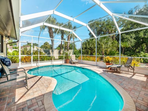 Private heated screened-in pool surrounded by lush tropical landscaping.