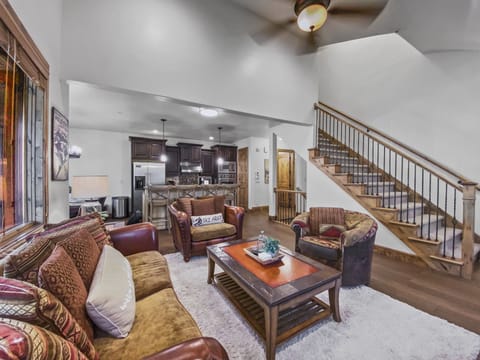 This cozy mountain lounge features a warm stone fireplace, plush seating, and vaulted ceilings. Relax with a movie or enjoy the natural light from large windows overlooking the trees.