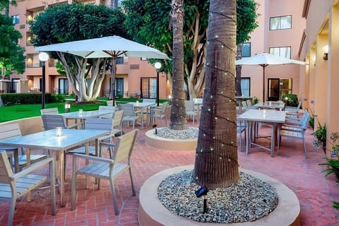 Sip morning coffee under umbrellas in the palm-lined courtyard.