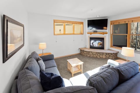 Sink into plush sofas by your crackling stone fireplace while natural light streams through windows overlooking peaceful woods.
