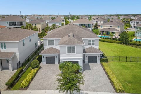 Beautiful aerial view of a modern home featuring garages and surrounded by manicured landscapes. The spacious property offers lush greenery and ample outdoor space, providing a peaceful and inviting retreat in a serene neighborhood.