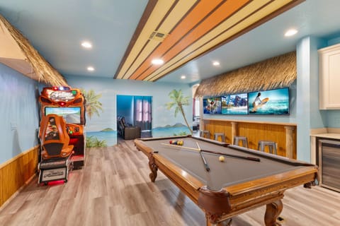 - Game room with pool table arcade racing game and tiki bar seating  
- Surfboard ceiling and tropical murals create a fun lively vibe  
- Indoor entertainment designed for families and groups