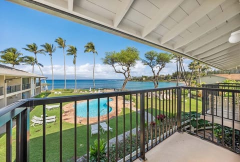 Shaded balcony with ocean and pool views — relax above tropical gardens and sparkling water.