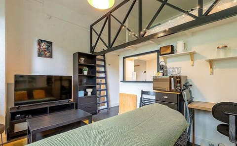 Pièce à vivre avec coin bureau, télé et canapé et quelques rangements