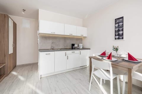 A white kitchen with built-in appliances, wooden shelves, and a clean, modern design.

