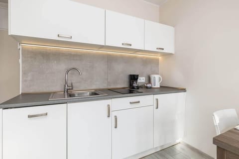 A close-up of the kitchen cabinets, showcasing a coffee maker and neatly arranged items.

