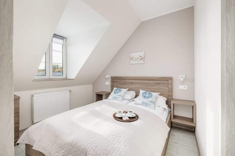 A cozy attic bedroom with a large bed, sloped ceiling, and soft lighting.

