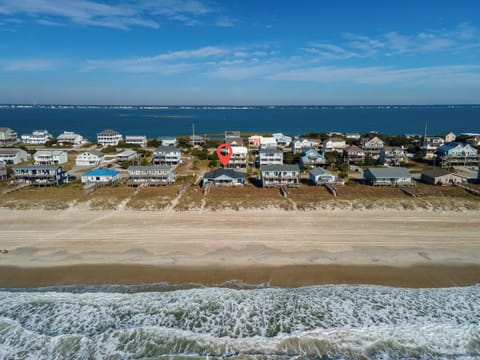 Oceanfront vacation homes line pristine sandy shores, with the highlighted property positioned perfectly between beach and bay waters.