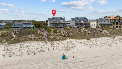 Beachfront vacation homes perched along pristine sandy shores with private beach access stairs and coastal dune views.
