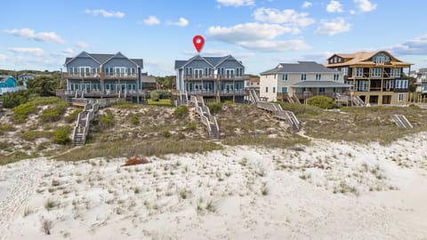 Beachfront homes with private walkways leading directly to pristine sandy shores under endless blue skies.
