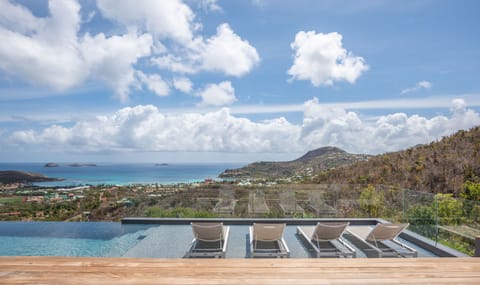 Heated pool surrounded by a spacious sun terrace with deckchairs. Spectacular view of the bay of St-Jean and hills.