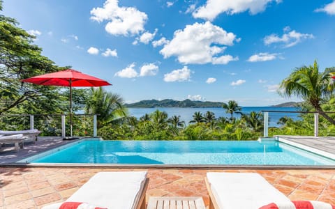Beautiful pool facing the view, corner with dining table, deck chairs, surrounded by tropical trees. 
