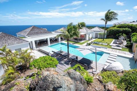 Heated pool surrounded by a sunny deck with deckchairs, gas barbecue.