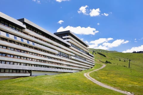 The Le Brelin building in summer, green slopes replacing snow and the mountains just as commanding.