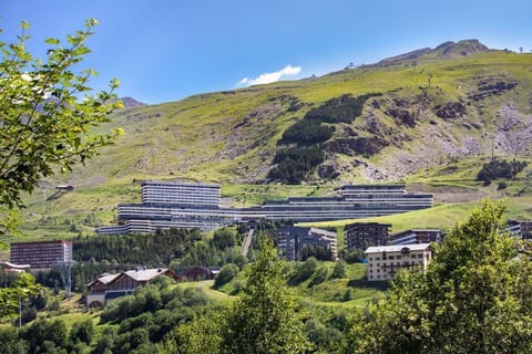 Stepped terraces rising into the green hillside — the residence sits right in the heart of Les Menuires.